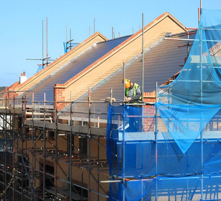 SAP Calculations Greater London SAP Calculation Greater London, SAP assessment Greater London, SAP Calculation near me, Construction worker on scaffolding at a new build housing site preparing for SAP energy assessment.